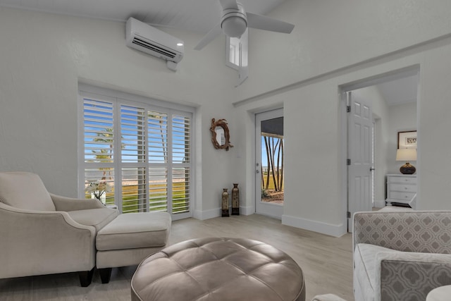 living area featuring light wood-type flooring, ceiling fan, baseboards, and a wall mounted air conditioner