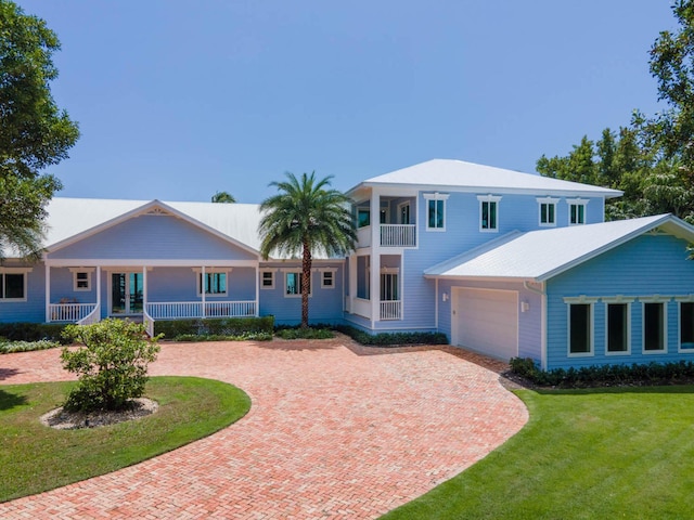 view of front of house featuring a balcony, covered porch, a garage, decorative driveway, and a front lawn