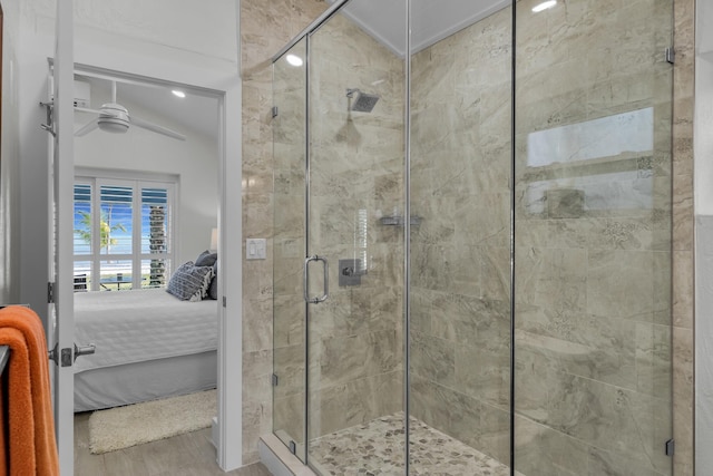 ensuite bathroom with a ceiling fan, a stall shower, ensuite bath, and wood finished floors