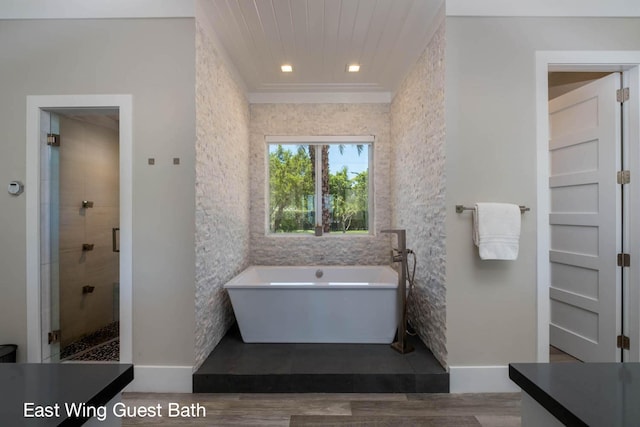 bathroom featuring wood finished floors, a stall shower, a freestanding tub, and vanity