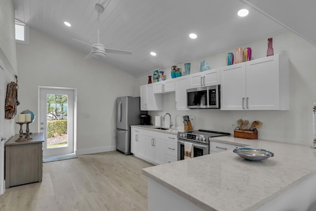 kitchen with a peninsula, appliances with stainless steel finishes, white cabinets, and a sink