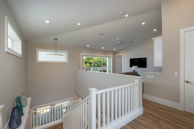 corridor featuring baseboards, vaulted ceiling, light wood-style flooring, and an upstairs landing