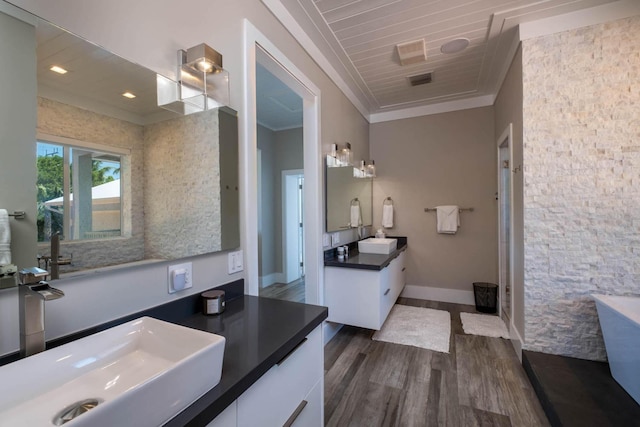 full bath with crown molding, two vanities, a sink, and wood finished floors