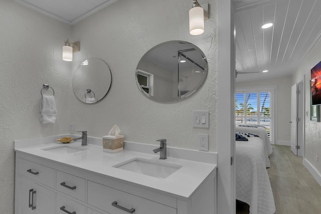 bathroom with a textured wall, connected bathroom, a sink, and double vanity