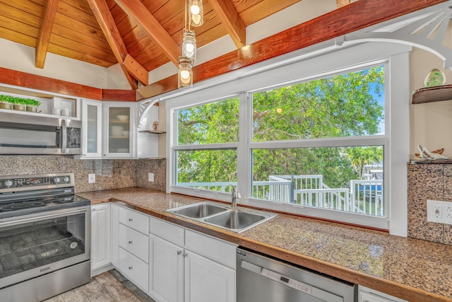 kitchen with open shelves, a sink, tile countertops, stainless steel appliances, and decorative backsplash