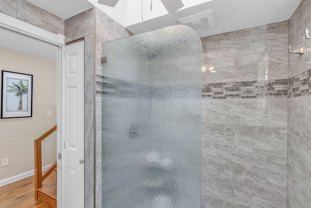 bathroom with wood finished floors, baseboards, and tiled shower