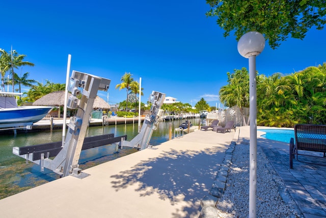 dock area with boat lift, an outdoor pool, and a water view