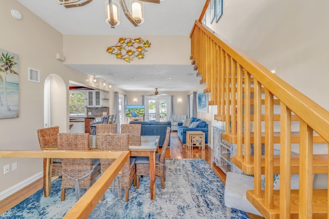 dining room featuring visible vents, baseboards, a chandelier, stairway, and wood finished floors