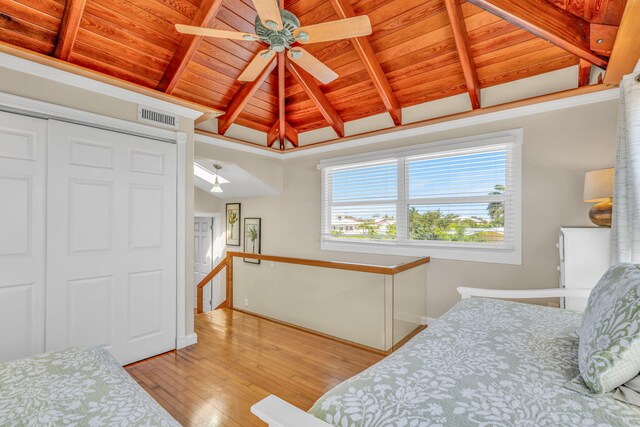 bedroom with visible vents, light wood-style flooring, a closet, wood ceiling, and vaulted ceiling with beams