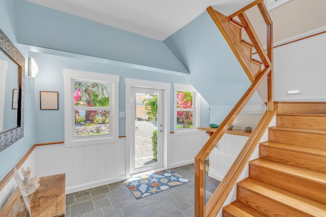 entryway featuring stairway, stone finish floor, and a wainscoted wall