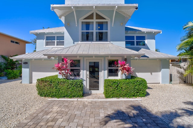 view of front facade featuring stucco siding, metal roof, and a standing seam roof