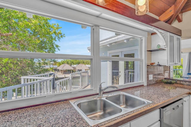 kitchen featuring backsplash, open shelves, stainless steel dishwasher, white cabinets, and a sink