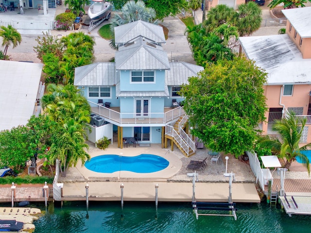 rear view of house with an outdoor pool, stairs, a water view, boat lift, and a patio area