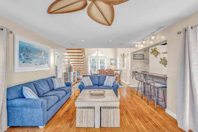 living room featuring rail lighting, light wood-style floors, and baseboards