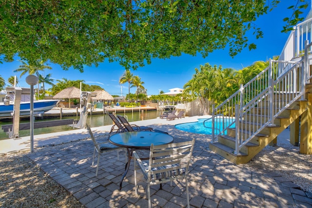 view of swimming pool featuring a fenced in pool, stairs, a dock, boat lift, and a patio