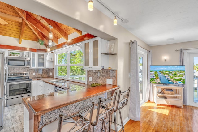 kitchen featuring decorative backsplash, stainless steel appliances, lofted ceiling with beams, and open shelves