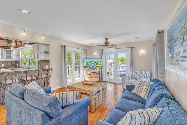 living room featuring a wealth of natural light, french doors, baseboards, and light wood-style floors