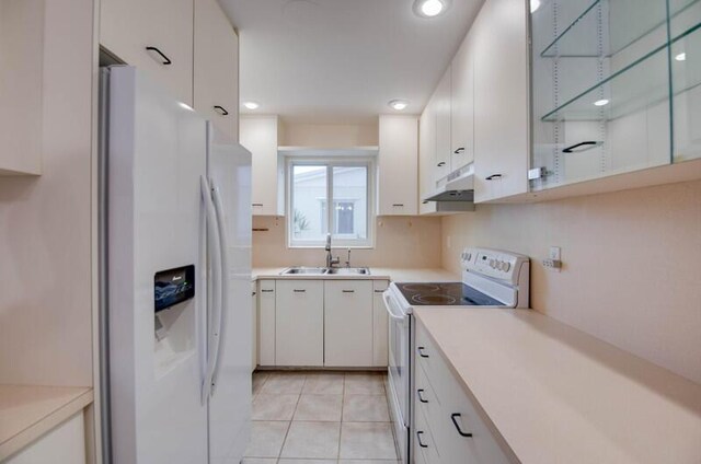 kitchen featuring white appliances, under cabinet range hood, light countertops, a sink, and white cabinetry