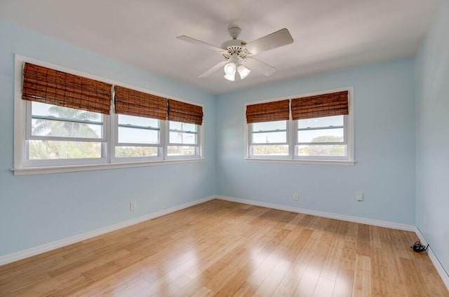 spare room with a ceiling fan, light wood-style flooring, and baseboards