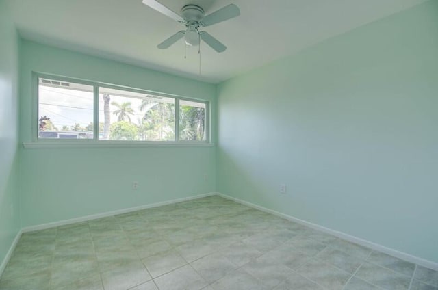 spare room featuring a ceiling fan and baseboards