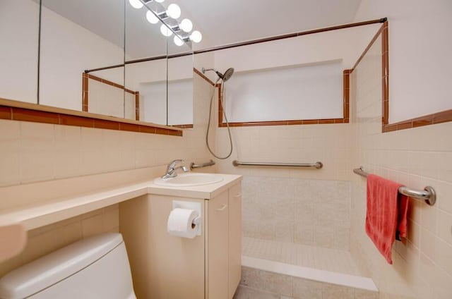 bathroom featuring toilet, tile walls, tiled shower, and vanity