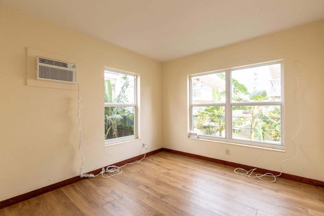 spare room featuring a wall mounted air conditioner, plenty of natural light, and light wood-type flooring