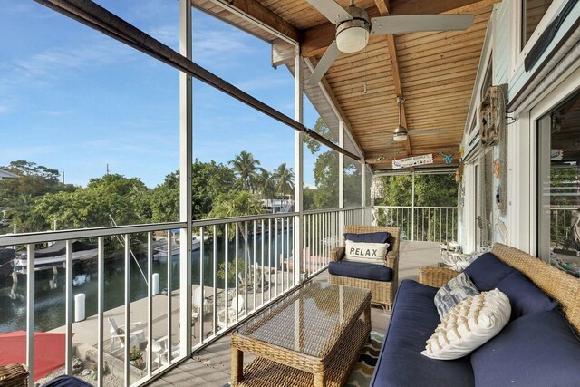 sunroom / solarium with lofted ceiling with beams, a water view, wooden ceiling, and ceiling fan