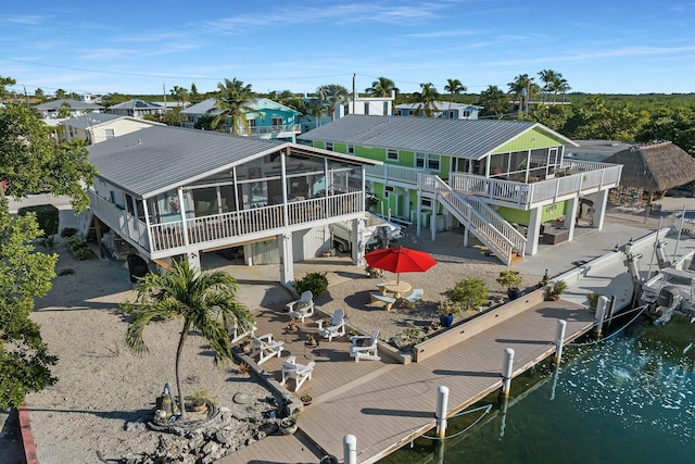 back of property with a deck with water view, a sunroom, and a patio