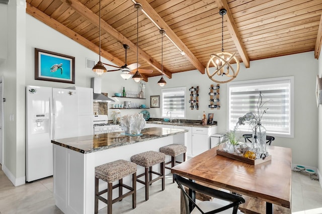 kitchen featuring pendant lighting, white appliances, white cabinets, a kitchen island, and dark stone counters