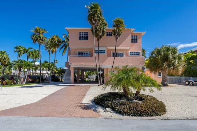 view of front facade featuring a carport, decorative driveway, stairway, and stucco siding