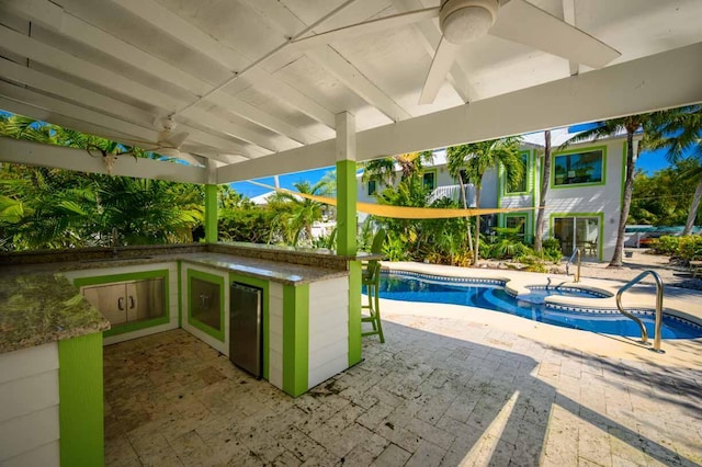 view of swimming pool with an in ground hot tub, a wet bar, ceiling fan, and a patio area