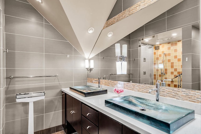 bathroom featuring a shower, tasteful backsplash, vaulted ceiling, tile walls, and vanity