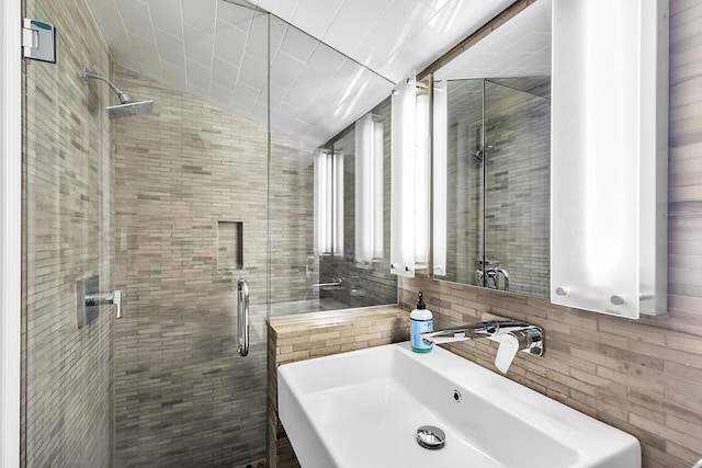 bathroom featuring tile walls, sink, vaulted ceiling, and a shower with door