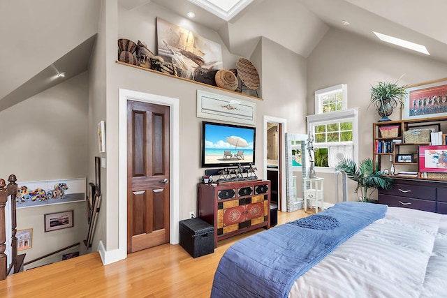 bedroom featuring high vaulted ceiling, light wood-type flooring, and a skylight