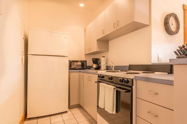 kitchen featuring white cabinetry, gas stove, white fridge, and light tile patterned flooring