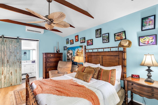 bedroom featuring lofted ceiling, ensuite bath, wood-type flooring, a wall mounted AC, and a barn door