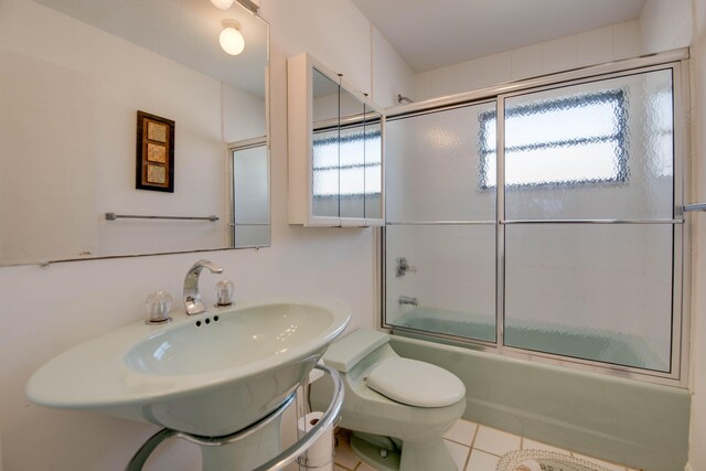 bathroom featuring tile patterned flooring, enclosed tub / shower combo, and toilet