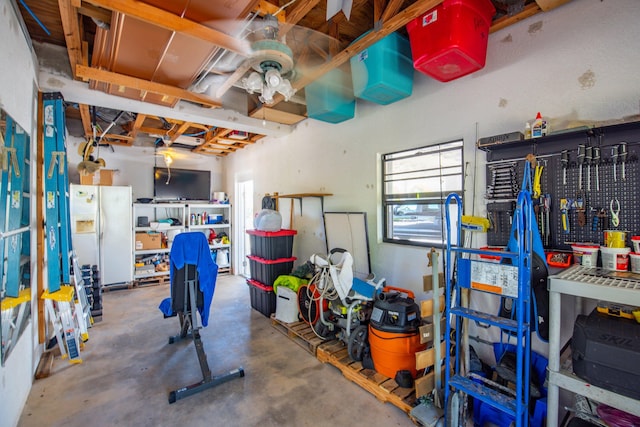 garage featuring white refrigerator with ice dispenser and a workshop area