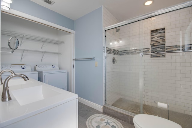 bathroom featuring an enclosed shower, sink, toilet, and washing machine and clothes dryer