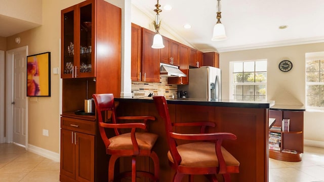97501 Overseas Hwy Unit 809, Key Largo, FL 33037 - kitchen featuring stainless steel fridge, under cabinet range hood, ornamental molding, light tile patterned floors, and decorative backsplash