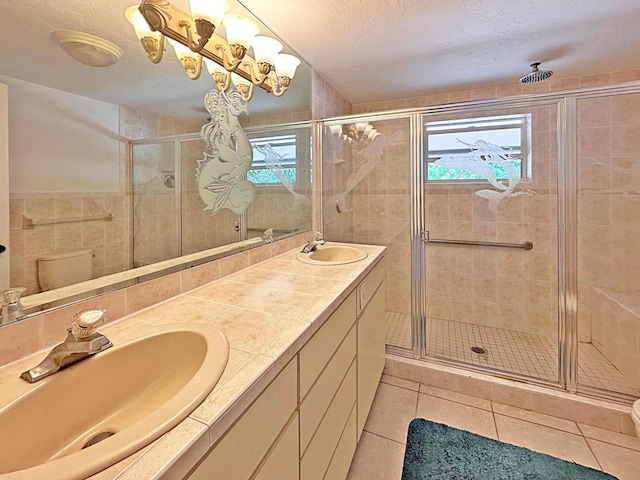 bathroom featuring a stall shower, tile patterned floors, double vanity, toilet, and a textured ceiling