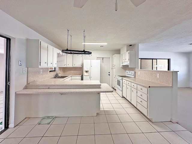 kitchen featuring white appliances, a peninsula, a sink, light countertops, and light tile patterned floors