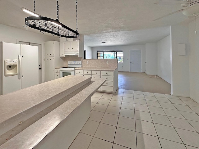 kitchen featuring white appliances, under cabinet range hood, light countertops, a peninsula, and white cabinets