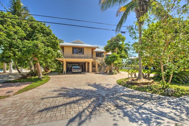 22865 Redfish Ln, Cudjoe, FL 33042 - coastal home featuring stairs, decorative driveway, a carport, metal roof, and covered porch