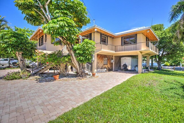 22865 Redfish Ln, Cudjoe, FL 33042 - view of front of home with a carport, stucco siding, decorative driveway, a front lawn, and a balcony