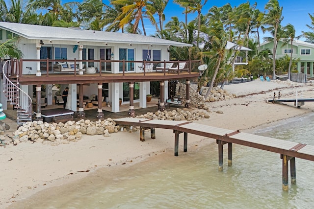 rear view of property featuring a deck with water view and a patio area