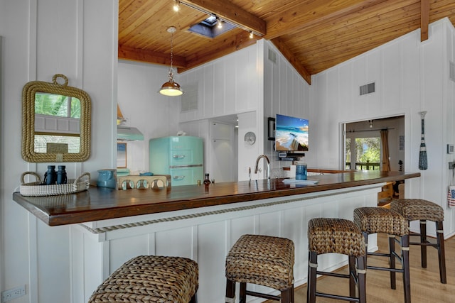 kitchen featuring hanging light fixtures, wooden ceiling, light hardwood / wood-style floors, and beamed ceiling