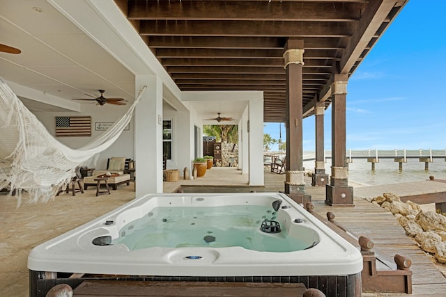 exterior space with a water view, an outdoor hot tub, and ceiling fan