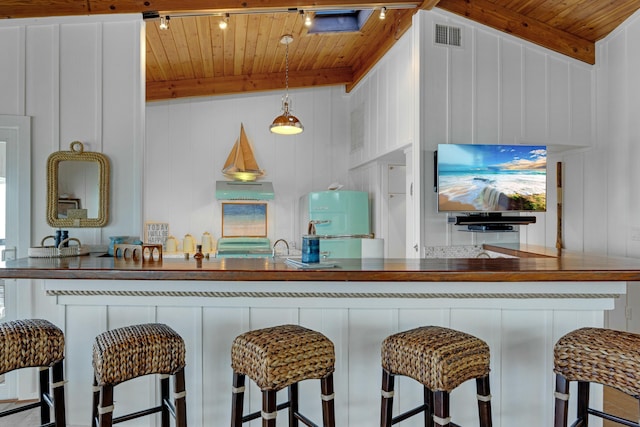 kitchen with hanging light fixtures, a breakfast bar area, wooden ceiling, and beam ceiling