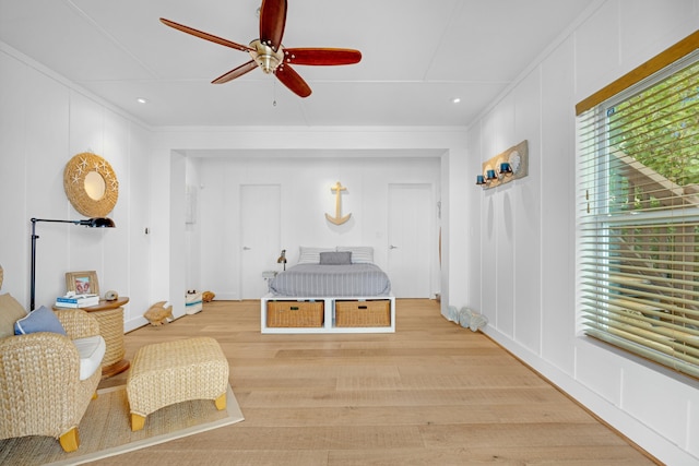 living area with crown molding, ceiling fan, and light hardwood / wood-style flooring